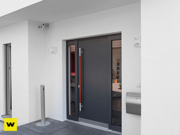 Moderne Haustür aus Aluminium mit Glaseinsatz an einem weißen, energieeffizienten Haus.